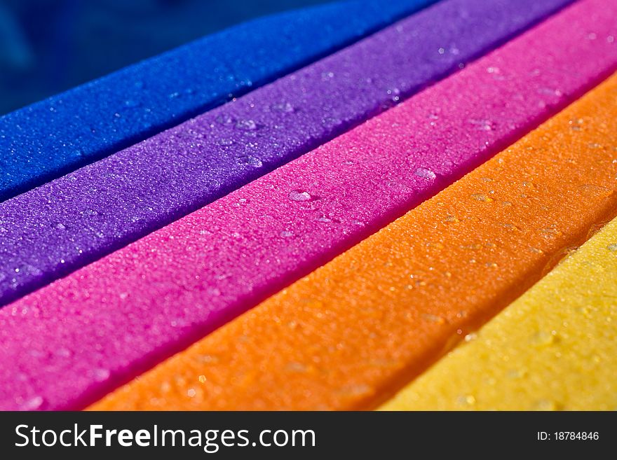 A rainbow colored water board in a pool with water on it. A rainbow colored water board in a pool with water on it