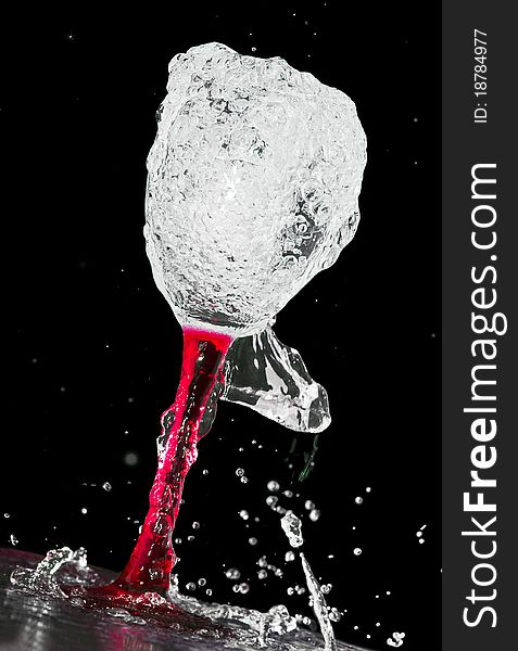 Red wine glass in a spray of water, a black background