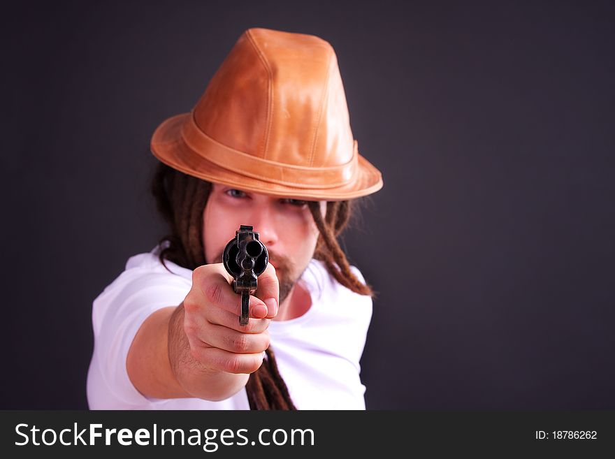 Dour guy wearing a hat holding a gun