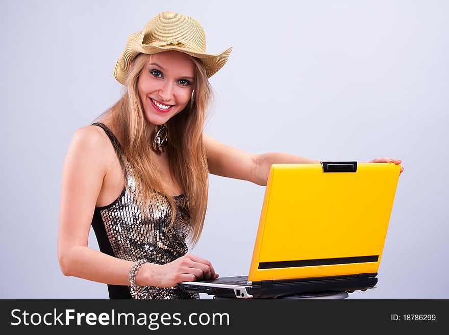 Attractive girl in a straw hat wth a yellow laptop