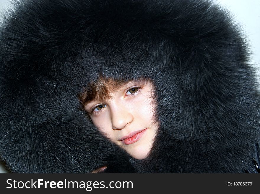 Portrait of the girl in a hood from dark grey fur of a polar fox. Portrait of the girl in a hood from dark grey fur of a polar fox