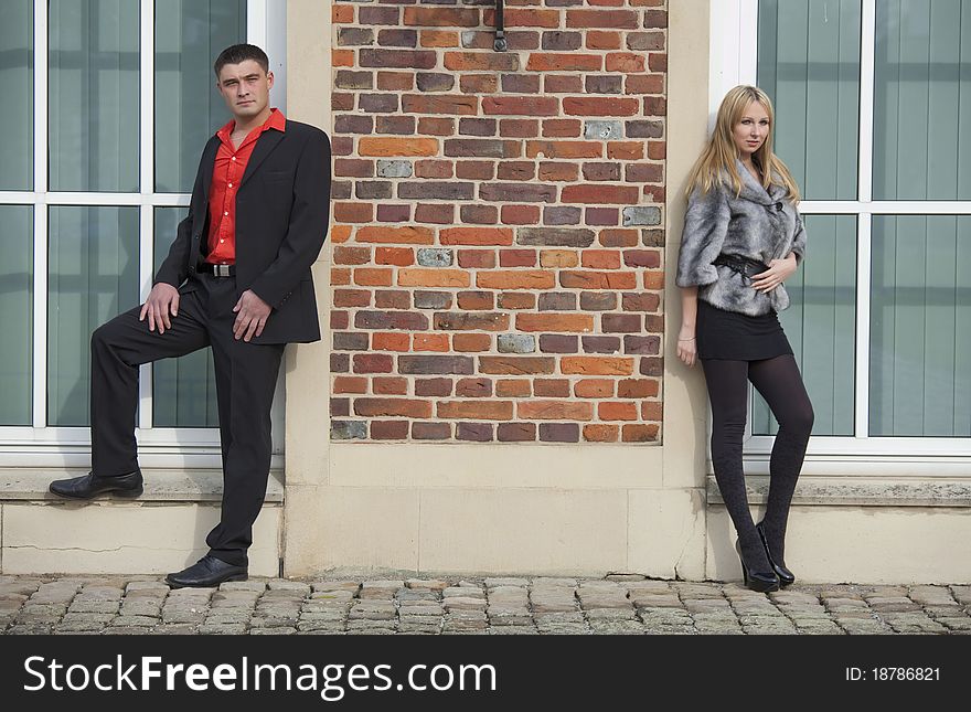 Young couple posing at the brick wall. Young couple posing at the brick wall