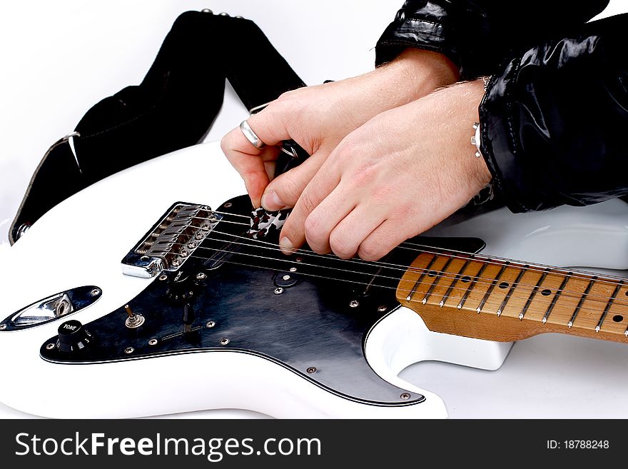 Person tuning a guitar from its headstock over white background