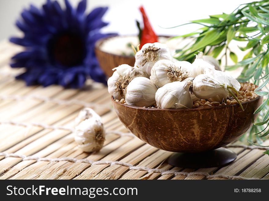 Closeup shot of white garlic pods over wooden mat.