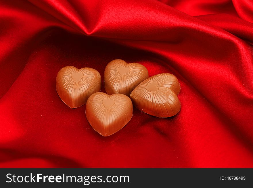 Candy hearts on red satin background