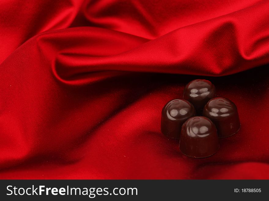 Chocolate candy on red satin background