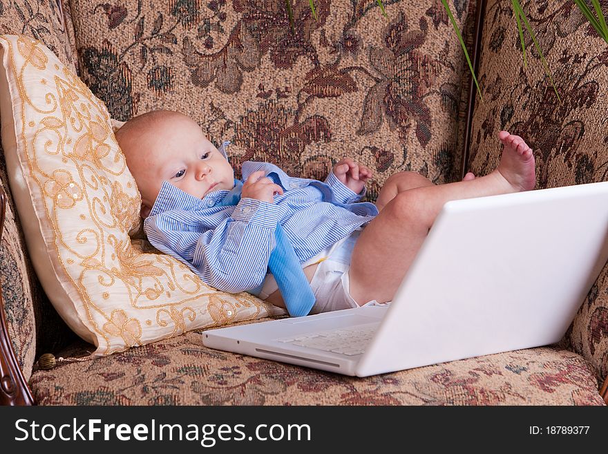 Serious businessman baby sits with the computer on sofa. Serious businessman baby sits with the computer on sofa