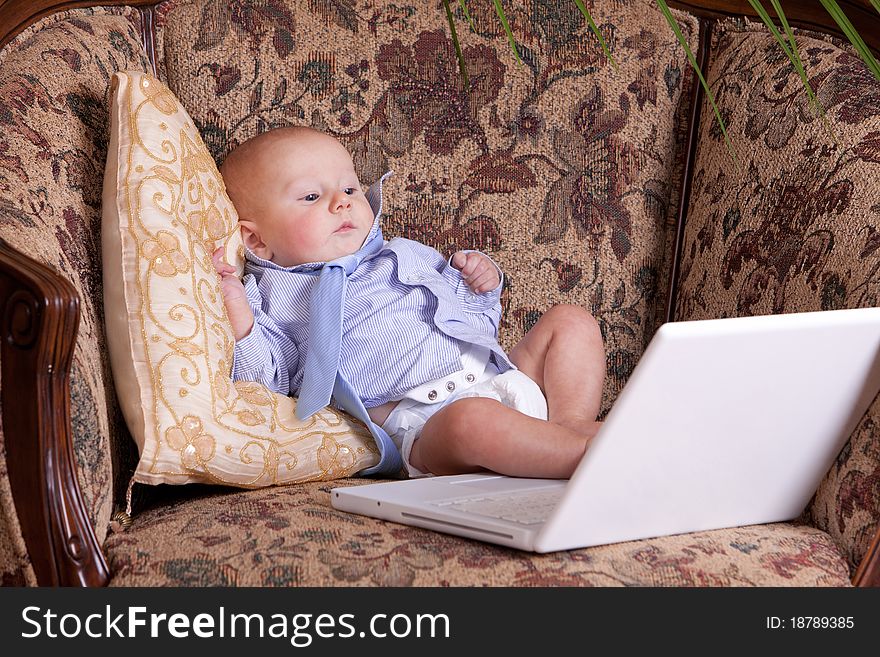 Serious businessman baby sits with the computer on sofa. Serious businessman baby sits with the computer on sofa