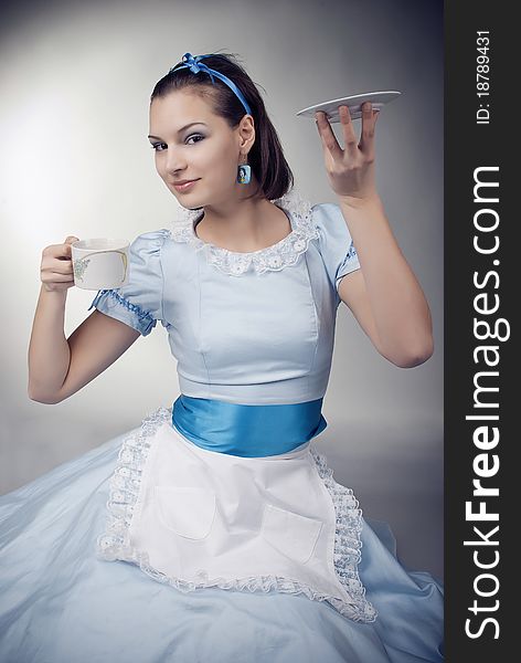 Girl dressed as the character of Alice having tea. Girl dressed as the character of Alice having tea