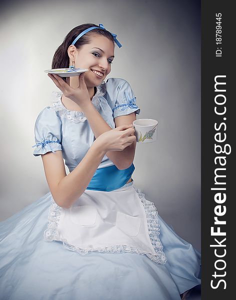 Girl dressed as the character of Alice having tea. Girl dressed as the character of Alice having tea