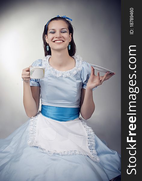 Girl dressed as the character of Alice having tea. Girl dressed as the character of Alice having tea