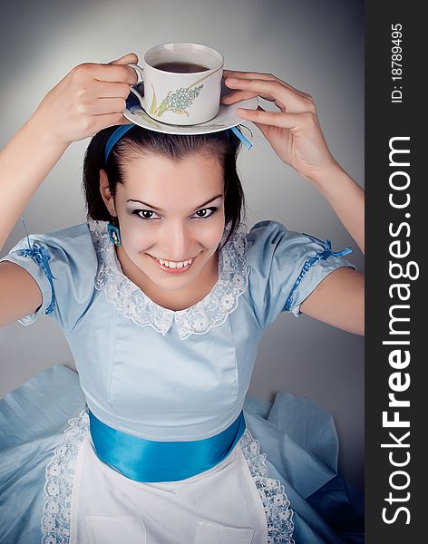 Girl dressed as the character of Alice having tea. Girl dressed as the character of Alice having tea