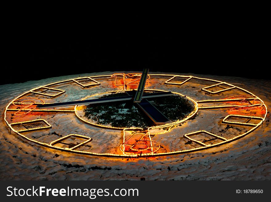 An outdoor clock with the lights in the winter night. An outdoor clock with the lights in the winter night