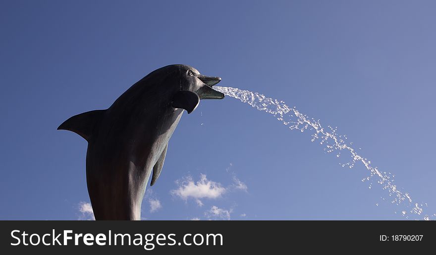 Dolphin fountain spitting on a blue sky