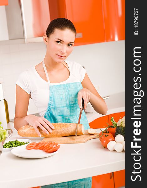 Young woman cutting bread on the kitchen