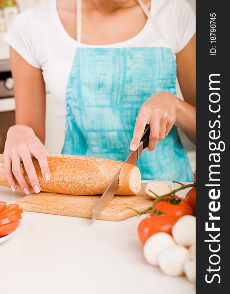 Woman Cutting Bread On The Kitchen