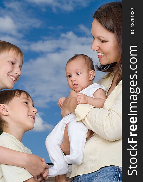 Young mother with three children at the background of the sky