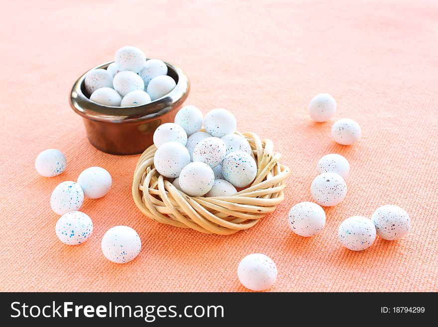 Miniature speckled easter eggs in two containers on an organce cloth