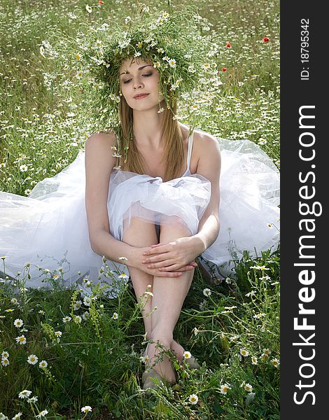 Young happy girl with daisy crown on head relaxing outdoors