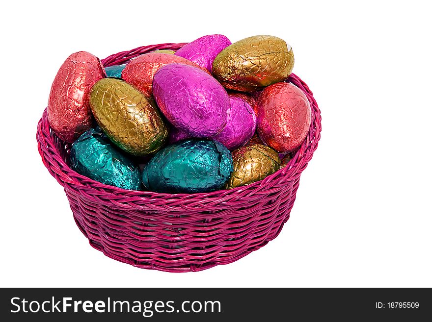 Colorful easter eggs wrapped in shiny foil in wicker basket isolated on white background. Colorful easter eggs wrapped in shiny foil in wicker basket isolated on white background