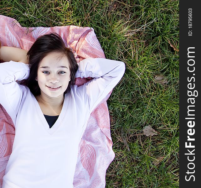 Young teen girl lie at grass. Outdoor shot.