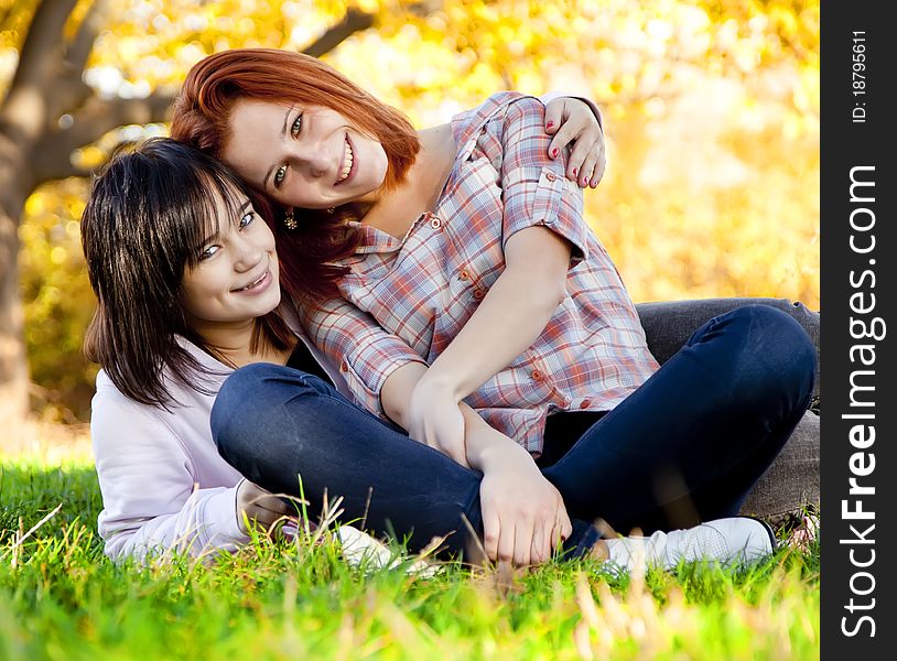 Two beautiful teen girl at green grass in the park.