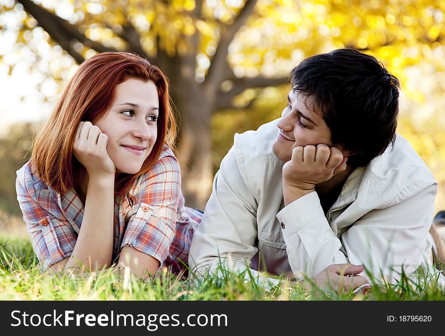 Young couple at grass in the park. Outdoor