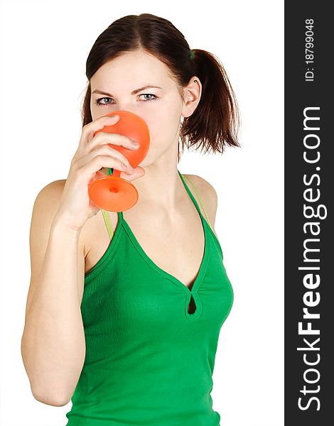 Young girl in green shirt drinking from orange glass, isolated