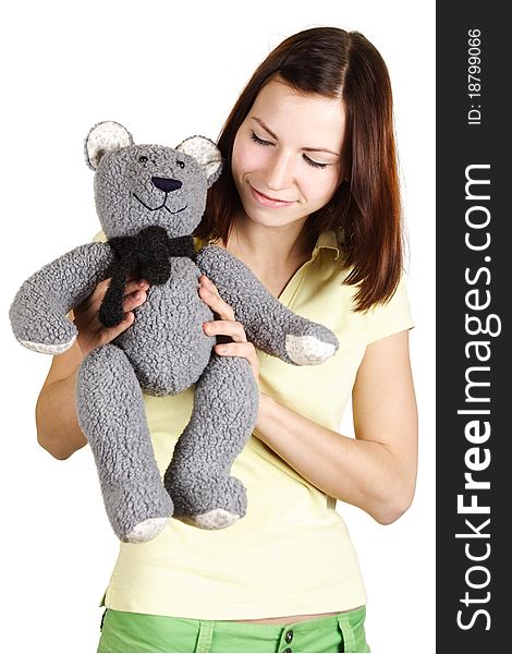 Young girl in yellow shirt holding soft bear toy, smiling and looking on it, isolated. Young girl in yellow shirt holding soft bear toy, smiling and looking on it, isolated