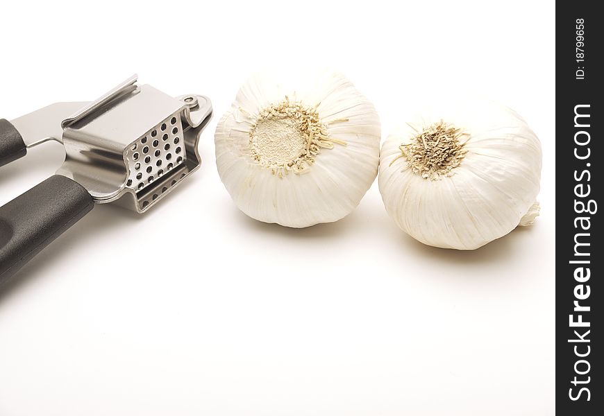 Garlic press and two cloves of garlic