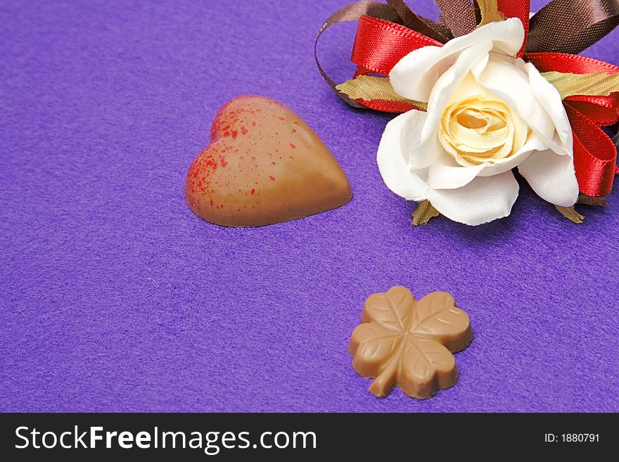 Still life with fancy Valentine chocolates and a rose over a violet background. Still life with fancy Valentine chocolates and a rose over a violet background.