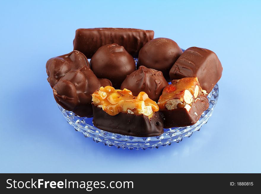 An assortment of chocolates arranged on a glass dish with a blue background. An assortment of chocolates arranged on a glass dish with a blue background.