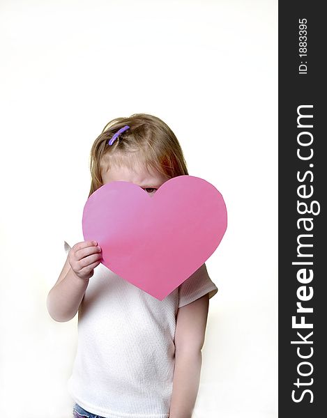 Little girl dressed in white holding a valentine heart. Little girl dressed in white holding a valentine heart