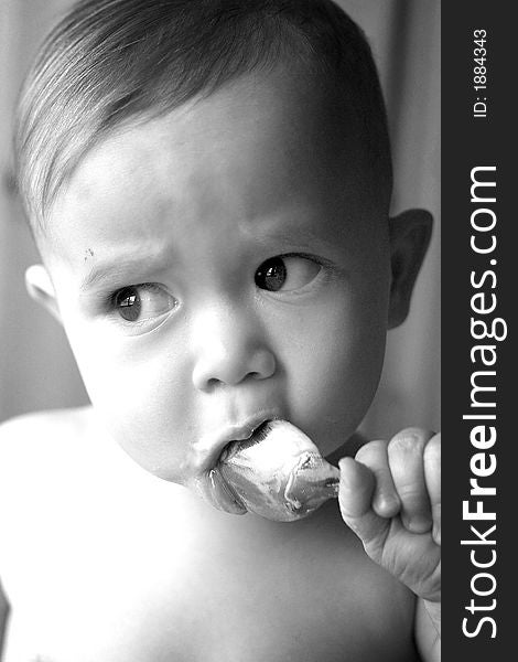 Black and white image of baby eating yogurt from a spoon. Black and white image of baby eating yogurt from a spoon