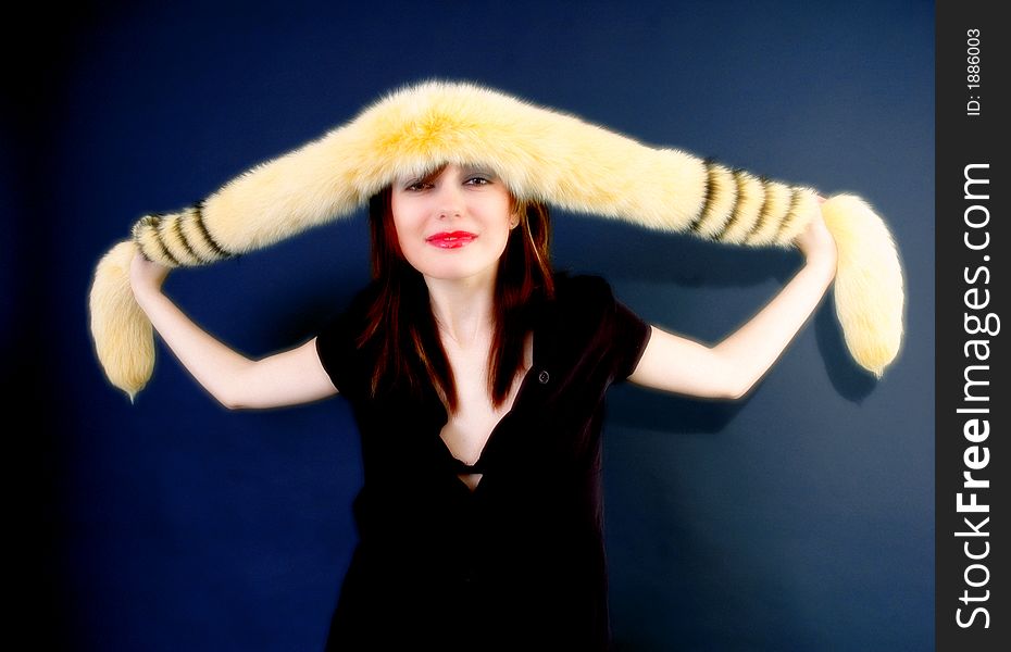 Portrait of a smiling young girl holding a furry yellow boa draped across her forehead.  Color enhancement.  Horizontal format.  . Portrait of a smiling young girl holding a furry yellow boa draped across her forehead.  Color enhancement.  Horizontal format.