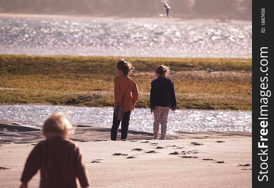 2 children standing at the seas edge, on a windy day. too cold to swim, but still a nice day for the beach. 2 children standing at the seas edge, on a windy day. too cold to swim, but still a nice day for the beach.