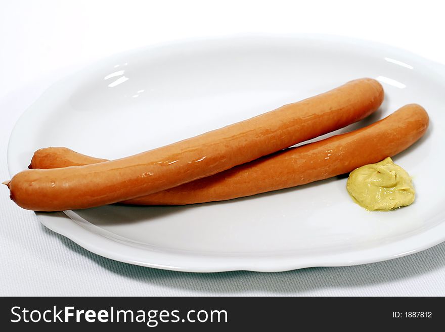 Pair of sausages on a plate with mustard. Pair of sausages on a plate with mustard