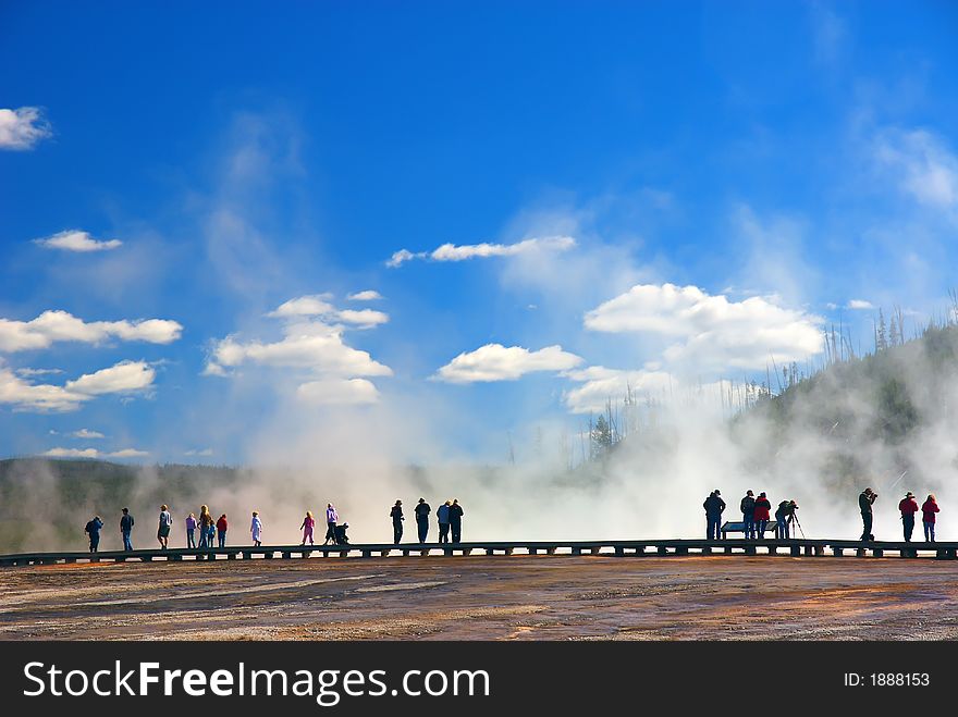 Tourist walking on edge of thermal pools in Yellowstone National Park. Tourist walking on edge of thermal pools in Yellowstone National Park