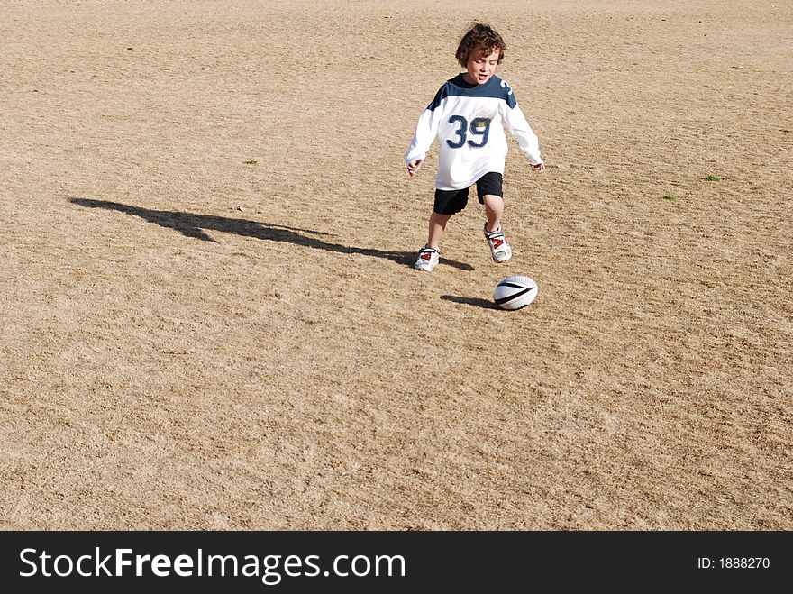 A boy chasing a football. A boy chasing a football