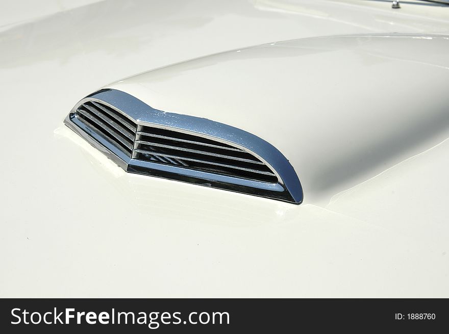 Close-up of chrome grille on air-scoop on hood of white sports-car. Close-up of chrome grille on air-scoop on hood of white sports-car