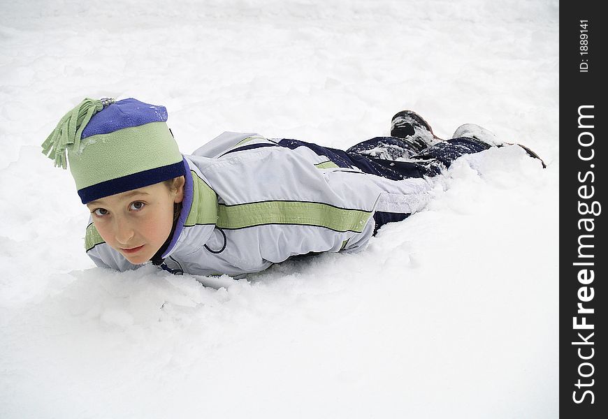 A warmly dressed kid lying in deep snow. A warmly dressed kid lying in deep snow.