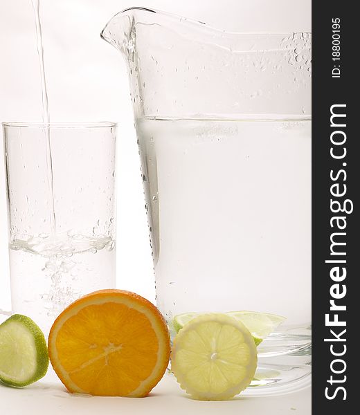Slice of Lemon, Lime and Orange with a glass and jug. The glass has water being poured into it. Slice of Lemon, Lime and Orange with a glass and jug. The glass has water being poured into it.