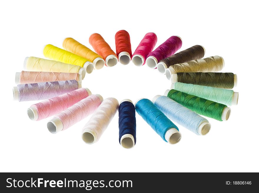 Circle of coloured bobbins of thread on white background. Circle of coloured bobbins of thread on white background