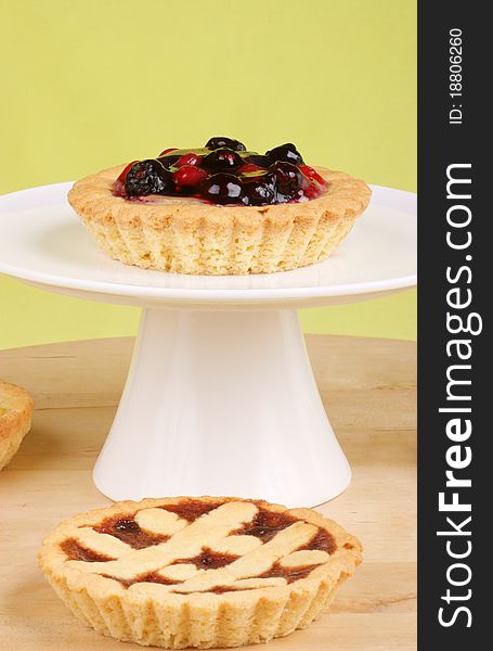 Small soft fruits tart served on a white cake stand. Small soft fruits tart served on a white cake stand