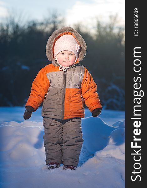 Adorable baby stay on top of hill in park with sun on back