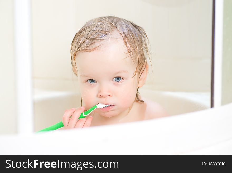 Adorable baby brushing teeth sitting in shower. Adorable baby brushing teeth sitting in shower