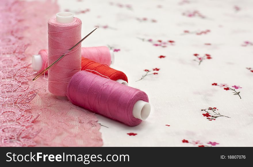 Pink spool of thread on a floral fabric
