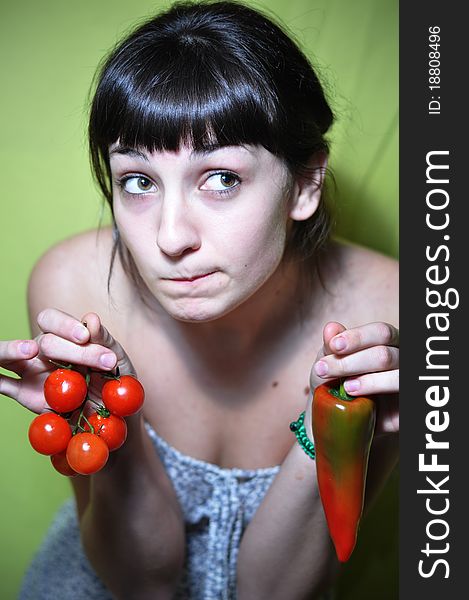 Girl holding tomato and pepper undecided. Girl holding tomato and pepper undecided