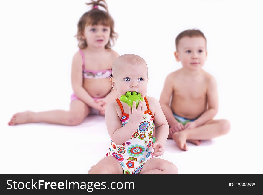 Two girls and one boy in swimsuit white background.Three small children play with toys. Two girls and one boy in swimsuit white background.Three small children play with toys.