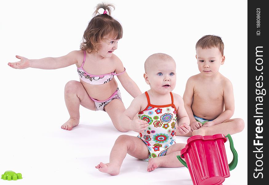 play with toys. Two girls and one boy sitting on a white background. play with toys. Two girls and one boy sitting on a white background.